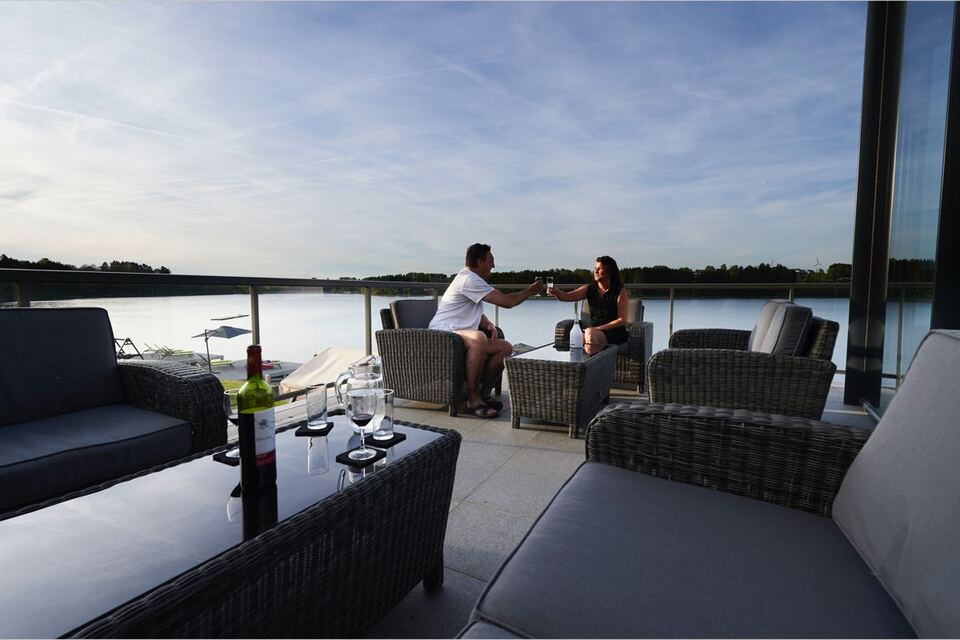Deux hôtes trinquent sur une terrasse avec vue sur le lac